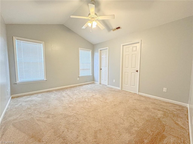 carpeted empty room with vaulted ceiling, ceiling fan, visible vents, and baseboards