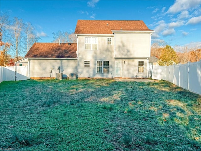 back of house with a fenced backyard and a lawn