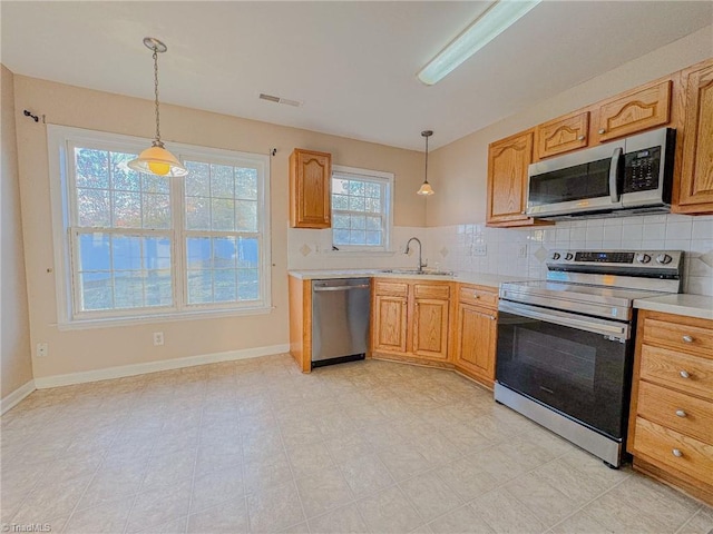 kitchen featuring a sink, light countertops, appliances with stainless steel finishes, tasteful backsplash, and decorative light fixtures