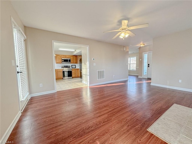 unfurnished living room featuring light wood finished floors, baseboards, and visible vents