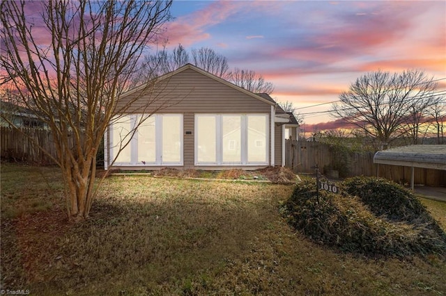 back house at dusk with an outdoor structure and a lawn