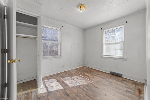 unfurnished bedroom with multiple windows, hardwood / wood-style floors, and a closet