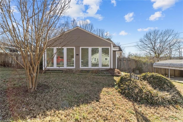 rear view of property featuring a carport and a lawn