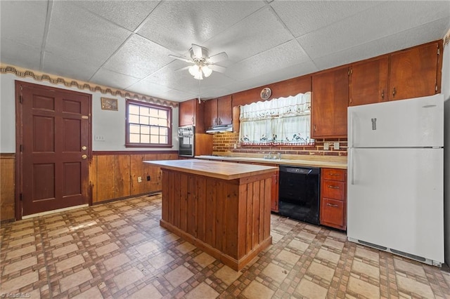 kitchen featuring a kitchen island, wooden walls, dishwasher, oven, and white fridge