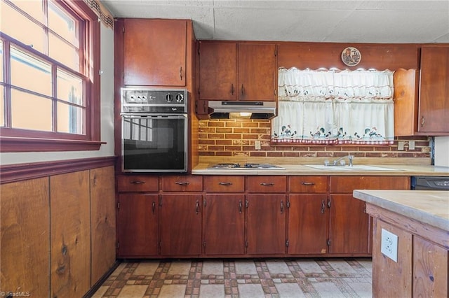 kitchen with sink, extractor fan, wood walls, tasteful backsplash, and black appliances