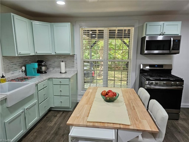 kitchen with sink, dark wood-type flooring, decorative backsplash, appliances with stainless steel finishes, and green cabinetry