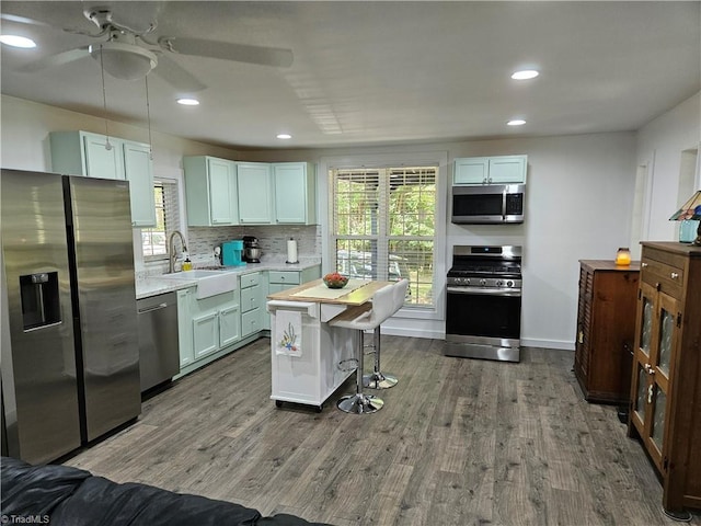 kitchen with stainless steel appliances, sink, dark hardwood / wood-style floors, a kitchen island, and a breakfast bar area