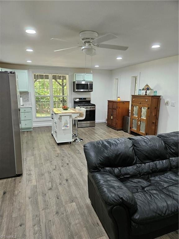 living room featuring light hardwood / wood-style floors and ceiling fan