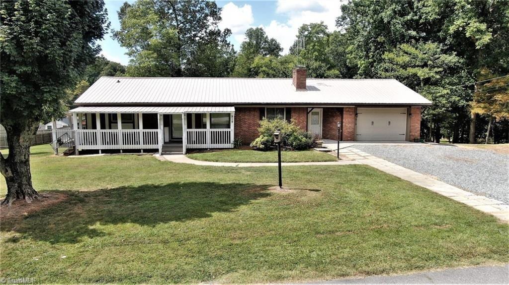 919 Overbrook Dr, Thomasville, NC 27360 - view of front facade featuring an attached garage, covered porch, brick siding, gravel driveway, and a chimney