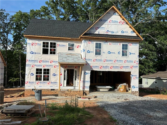 property in mid-construction featuring an attached garage, driveway, and roof with shingles