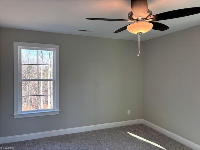 unfurnished room with carpet floors, visible vents, ceiling fan, and baseboards