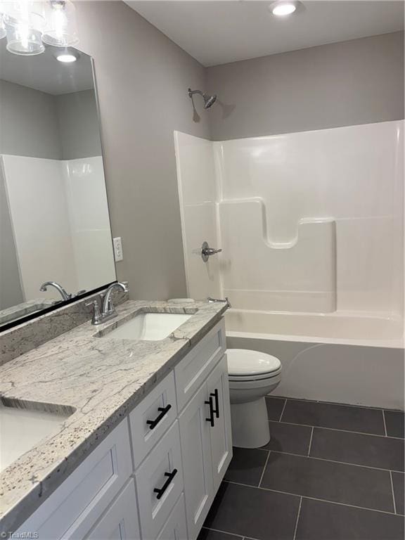 bathroom with a sink, washtub / shower combination, double vanity, toilet, and tile patterned flooring