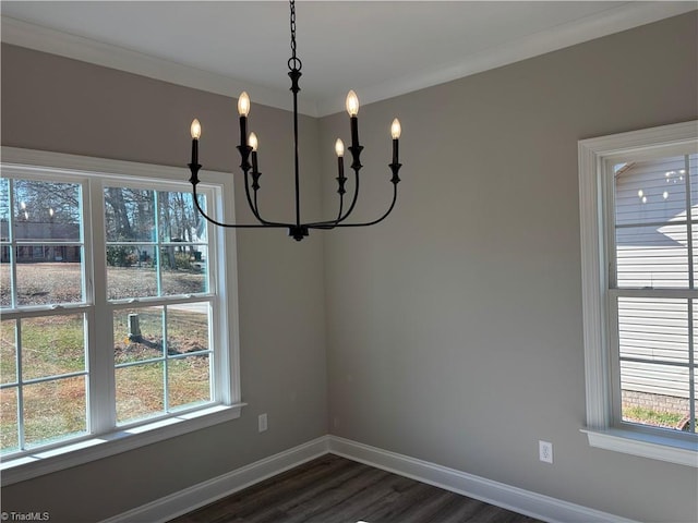 unfurnished dining area featuring a chandelier, a healthy amount of sunlight, dark wood-style flooring, and baseboards