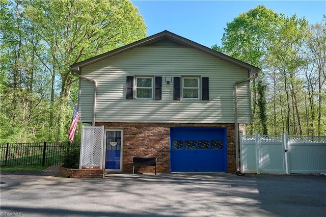 6130 Narrow Way Ln, Winston-Salem, NC 27105 - view of front of home with asphalt driveway, a garage, brick siding, and fence