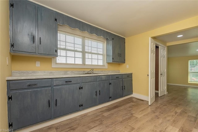 kitchen with light wood-type flooring, gray cabinets, and sink