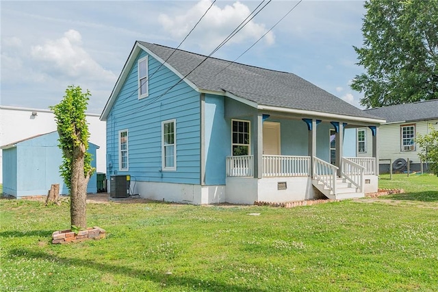 view of front facade with covered porch, a front yard, and central AC