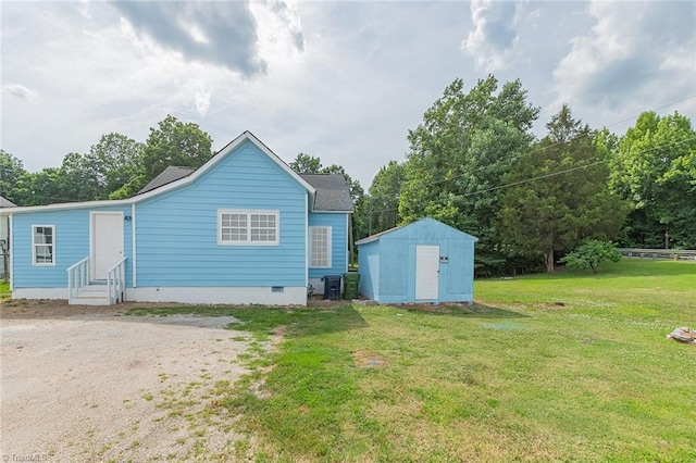 back of property featuring a lawn, central AC, and a storage unit