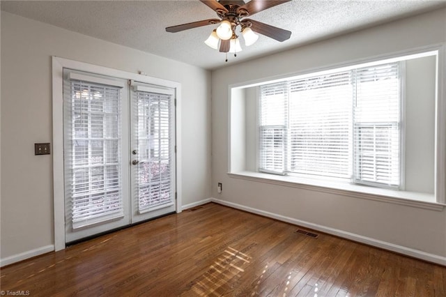 empty room featuring french doors, ceiling fan, dark hardwood / wood-style floors, and a textured ceiling