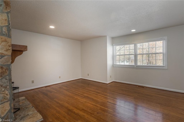 unfurnished living room featuring dark wood-type flooring and a textured ceiling