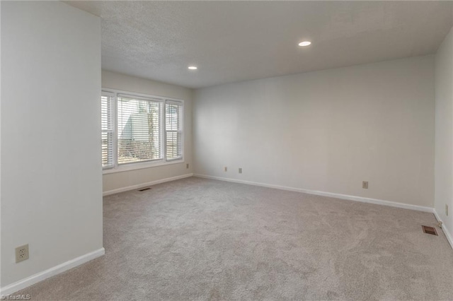 carpeted empty room featuring a textured ceiling