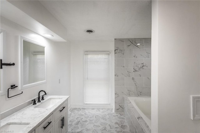 bathroom featuring a relaxing tiled tub and vanity