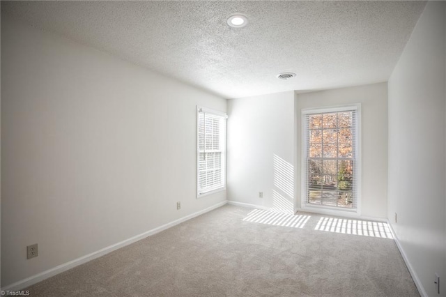 carpeted empty room with a textured ceiling