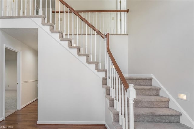 stairway featuring a towering ceiling and hardwood / wood-style floors