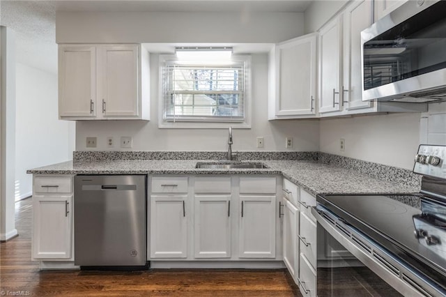 kitchen with white cabinetry, stainless steel appliances, light stone countertops, and sink