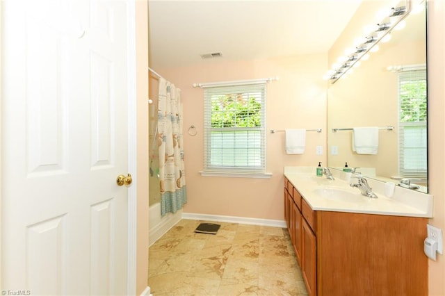 3920 Gisbourne Dr, Jamestown, NC 27282 - bathroom with double vanity, baseboards, and shower / bathtub combination with curtain