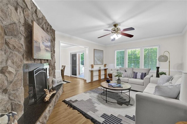 living room with crown molding, light wood finished floors, ceiling fan, and a fireplace