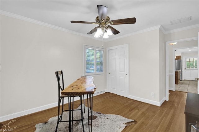 dining area with ceiling fan, baseboards, wood finished floors, visible vents, and ornamental molding