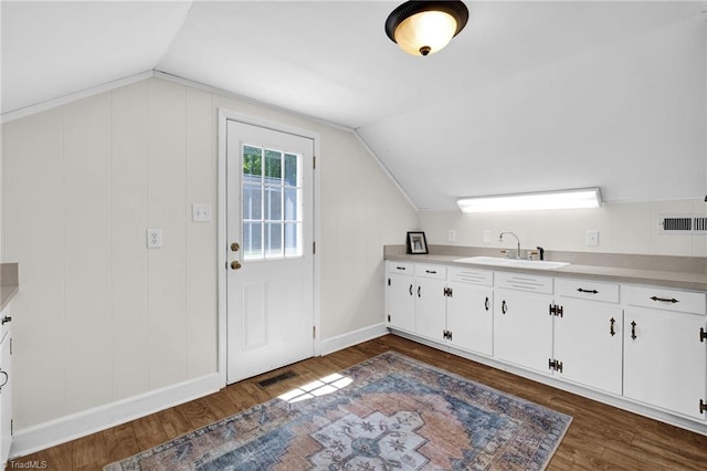 kitchen with dark wood-style flooring, light countertops, white cabinets, a sink, and vaulted ceiling