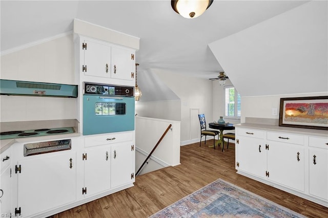 kitchen featuring under cabinet range hood, light wood finished floors, wall oven, and lofted ceiling