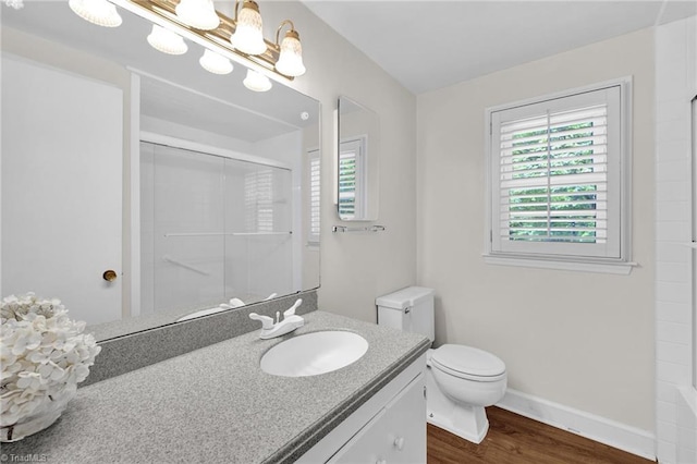 bathroom featuring a shower, wood finished floors, vanity, baseboards, and toilet
