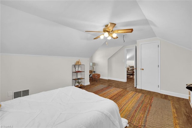 bedroom featuring a ceiling fan, visible vents, vaulted ceiling, wood finished floors, and baseboards