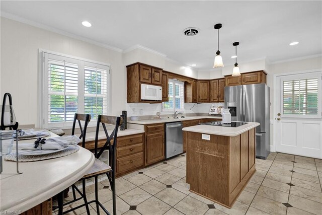 kitchen with hanging light fixtures, light countertops, stainless steel appliances, a kitchen island, and ornamental molding
