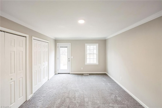 unfurnished bedroom with multiple closets, carpet floors, and ornamental molding