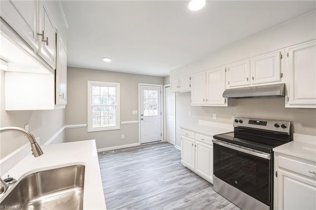 kitchen with stainless steel electric stove, white cabinetry, sink, and light wood-type flooring