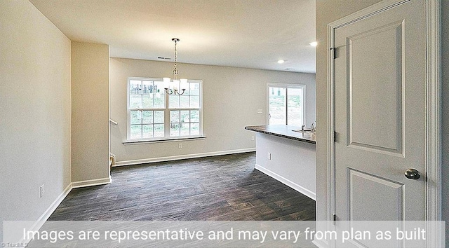 unfurnished dining area featuring dark wood-type flooring, a notable chandelier, and sink