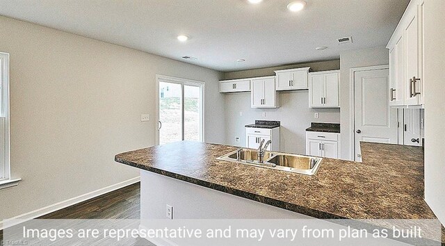 kitchen featuring kitchen peninsula, dark wood-type flooring, sink, and white cabinetry