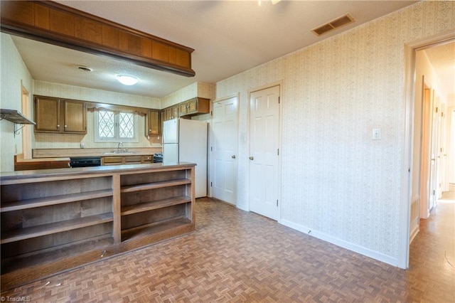 kitchen with baseboards, visible vents, wallpapered walls, freestanding refrigerator, and a sink