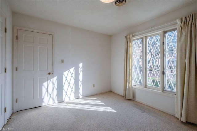 carpeted spare room featuring visible vents and a textured ceiling