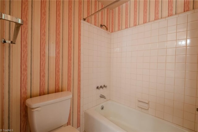 bathroom featuring toilet, wallpapered walls, and shower / tub combination