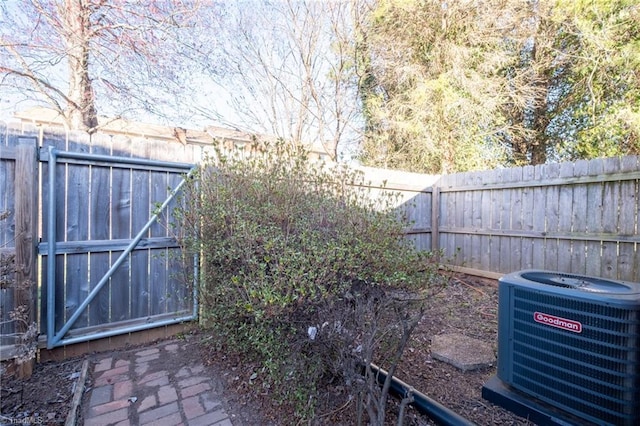 view of yard featuring a fenced backyard, central AC, and a gate