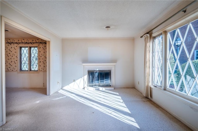 unfurnished living room featuring a glass covered fireplace, plenty of natural light, a textured ceiling, and carpet flooring