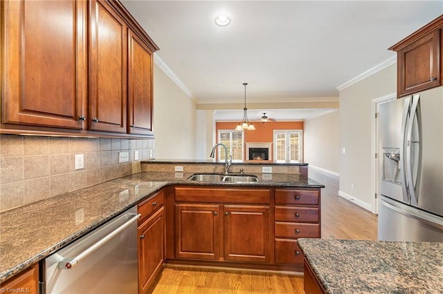 kitchen featuring ornamental molding, appliances with stainless steel finishes, sink, and dark stone countertops