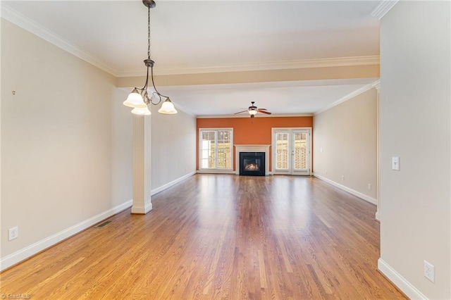 unfurnished living room featuring wood-type flooring, ceiling fan with notable chandelier, and crown molding