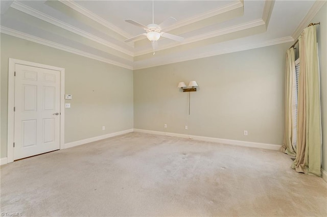 empty room featuring ceiling fan, ornamental molding, a raised ceiling, and light carpet