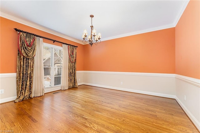 empty room with crown molding, a notable chandelier, and light hardwood / wood-style floors