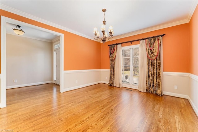 unfurnished room with crown molding, light hardwood / wood-style floors, and a notable chandelier